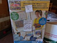Front box of Melissa & Doug Multi Craft Loom showing product name, images of the loom, and a child using the loom. Box has a MaxSold label and minor plastic packaging tears visible.