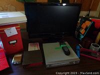 View of TV, DVD player, remote, red file box, patterned box, and other office supplies on a table.