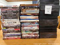 Photo showing three stacks of DVDs and a pile of 30 empty black DVD cases.
