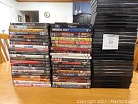 Photo showing stacked DVDs and a large pile of empty DVD cases on a wooden table