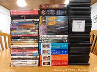 Photo showing full lot of DVDs stacked and 30 empty DVD cases on right.