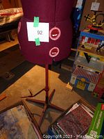 Front view of burgundy Singer 151 dress form on stand with fabric boxes at base