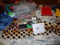 Overview of sewing materials including fabric, containers of buttons and zippers, and reading glasses.