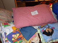 Red and white gingham pillowcase, Winnie the Pooh sheet, blue cloth, Dora throw blanket shown together