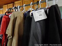Hanging clothing in various colors and fabrics including beige, black, gray, and a red-coral shirt, size labeled 46 for women's size 16.
