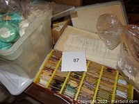 Plastic container holding balls of green crochet mercerized cotton thread on top of a red thread box.