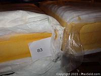 Two new yellow high density foam cushions partially wrapped in white fabric and plastic, with a measurement tag '83' visible.