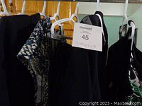 Hanging clothing items on hangers showing several navy and dark-colored pieces including pants, a dress, and overcoat.