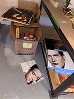 Box containing vinyl albums and CDs, vinyl albums on top showing different artist covers.