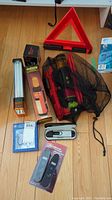 Photo of the safety triangle, lock de-icer, packaged emergency triangles and one digital tire gauge in blister packaging along with another gauge on the floor