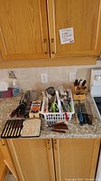 Kitchen counter showing assortment of kitchen tools, utensils, BBQ tools, and GrillPro chicken roaster box
