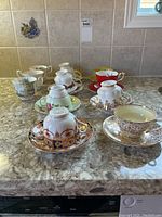 Full assortment of teacups and saucers in various styles and brands displayed on kitchen counter.