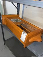 Side angle showing wooden case with clear glass panels and decorative molding