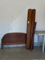Wooden footboard and side rails leaning against wall in garage