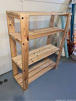 Wooden shelving unit showing overall structure and four slatted shelves in a basement setting.