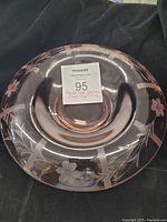 Top-down view of round pink depression glass serving dish with etched floral and geometric patterns, no damage visible.