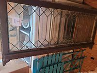 Full view of the wooden framed stained glass window with diamond pattern glass panes.