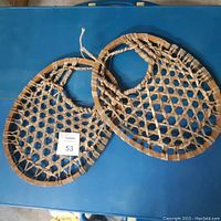 Pair of vintage round snow shoes on a blue surface showing their full shape and design.