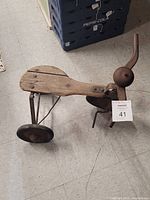 Side and top view of the vintage wooden child's tricycle showing wooden seat, metal wheels, and handlebar with bell.