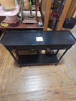 Wooden black hall table with two drawers in closed position viewed from above showing flat top and front face with ring handles.
