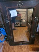 Full view of the rectangular mirror showing dark wooden frame with gold ornamental accents and reflective glass surface.