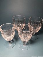 Four Waterford crystal stem glasses—two larger and two smaller—showing cut diamond patterns and stems.