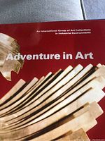 Front cover of the book showing title 'Adventure in Art' with a sculptural artwork in beige tones on a red background.