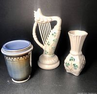 Front view of three Belleek Irish porcelain pieces including a bud vase, harp, and cup.