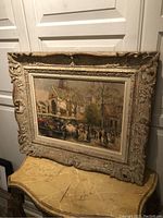 Full view of framed painting leaning against panelled wall