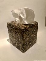 Front view of marble tissue cover with white tissues inserted, showing cube shape and pebble pattern.