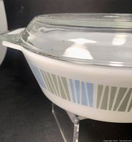 Side angle showing the white glass Pyrex dish with blue and gray geometric pattern on sides and clear glass lid on top.