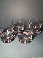 Four clear, crystal lowball glasses arranged, showing thickness and clarity of glass.