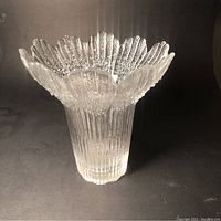 Front view of the textured clear glass flower vase showing flared petal rim and vertical ribbed body.