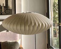 Front view of saucer-shaped pleated fiberglass lamp hung in room