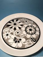 Full view of the round ceramic tray showing the black and white flower pattern with white rim.