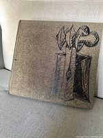 Dark brown cloth-covered book with abstract line drawing on front cover, sitting on beige fabric surface.