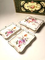 Photo of the three porcelain pieces, two trays and one lidded dish, with original box in background.