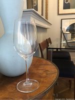 Single clear stemmed wine glass on a wooden table, showing the shape and clarity of the glass.