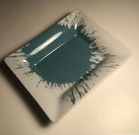 Rectangular porcelain trinket tray with turquoise splash design and white background.