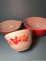 Three vintage Pyrex bowls with different designs and colors placed together showing their sizes and styles