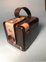 Angled view of the black and silver box-style vintage camera showing carry handle on top and front mechanical components.