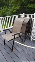 Side view of the brown outdoor folding chair showing mesh fabric seat and back with metal armrests and frame