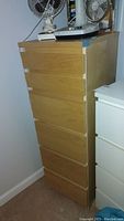 Front view of the tall veneer dresser with drawers closed, showing light wood finish.