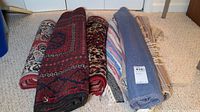 Six rolled rugs displayed side by side on floor