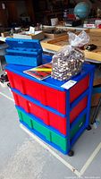 Full view of the plastic storage unit on casters with drawers, bag of wooden beads, and blue tackle box on top.