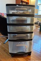 Frontal view of five-drawer storage unit showing translucent drawers with black casing, drawers tagged with labels and slightly open revealing emptiness.