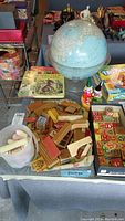 Vintage wooden building blocks, children's books, globe, and chalk container shown on a table.