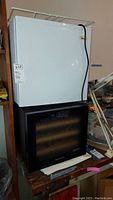 Front view of stacked Magic Chef mini fridge on top of Wine Enthusiast wine fridge