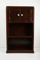 Front view of the dark wooden cabinet shelf showing two white-knobbed doors and two open shelves below