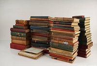 Large stacked assortment of antique and vintage hardcover books showing variety in size and binding colors